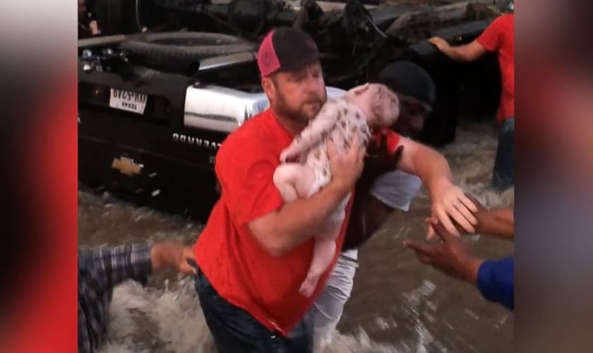Homem retira o bebê desacordado do carro que estava preso na correnteza. (Foto: Reprodução/Facebook)