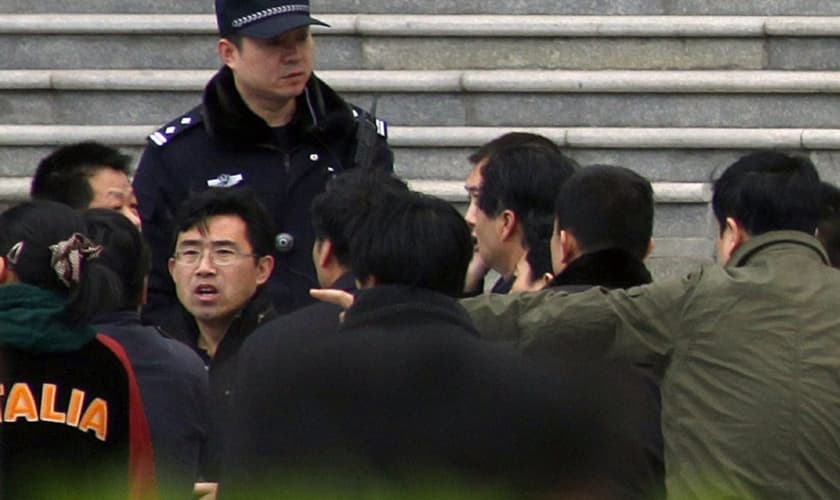 Policiais à paisana cercam um homem que estava dentro de uma igreja, em Pequim. (Foto: David Gray/Reuters)