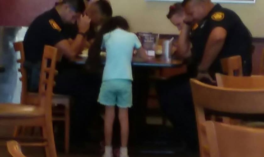Menina de 8 anos ora por policiais que tiveram companheiro assassinado. (Foto: Reprodução/Facebook)