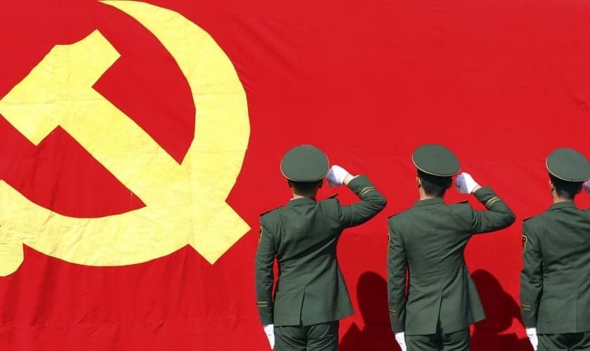 Membros do Partido Comunista em atitude de reverência à bandeira comunista. (Foto: Financial Times)