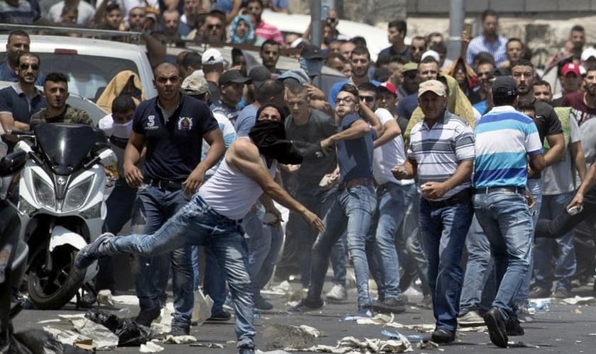 Manifestante palestino joga pedra contra as forças de segurança israelenses. (Foto: Jack Guez/AFP)