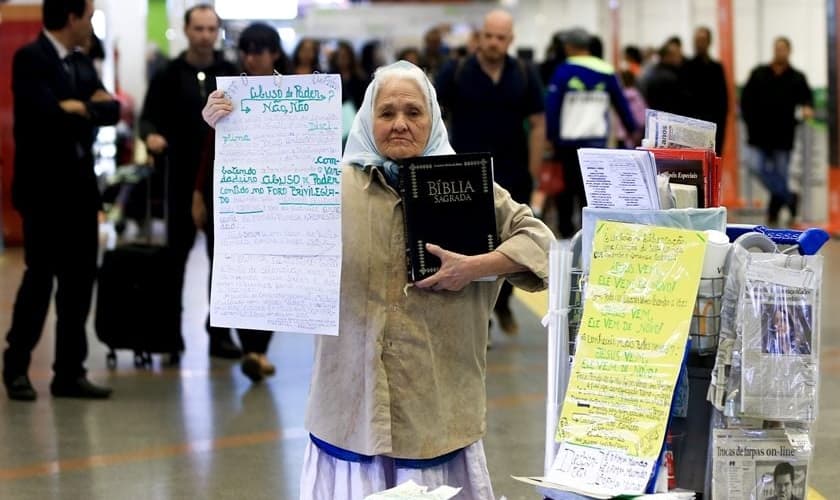 Sem ouvir desde os 38 anos, Dona Isaura carrega a Bíblia e cartazes. (Foto: Rafaela Felicciano/Metrópoles)