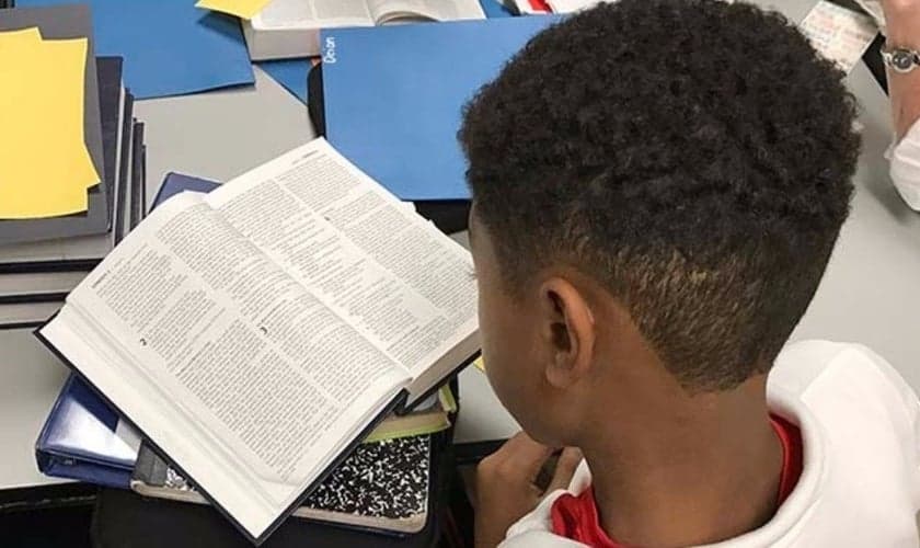 Garoto lendo a Bíblia. (Foto: Bible in The Schools)