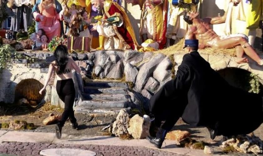 Feminista corre em direção ao presépio, enquanto é seguida por policial, no Vaticano. (Imagem: REUTERS VIDEO)