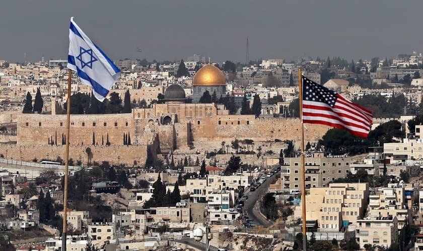 Bandeiras de Israel e dos EUA são vistas no telhado de um prédio em Jerusalém Oriental. (Foto: Ahmad Gharabli/AFP)