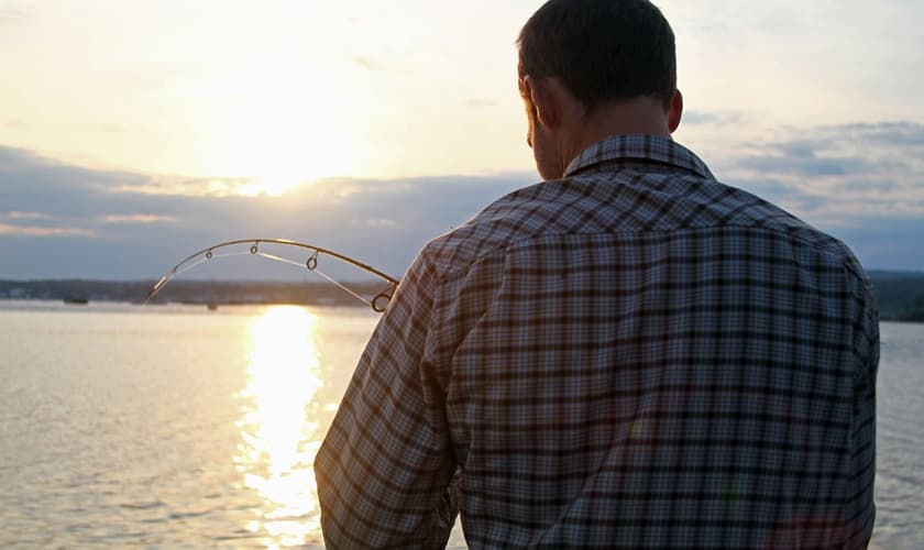 Imagem ilustrativa. Homem de costas para a câmera ajustando sua linha de pesca. (Foto: Nicko Margolies)