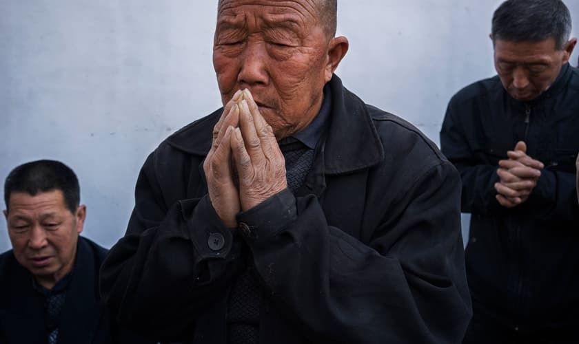 Chineses orando em uma igreja subterrânea no quintal de uma casa. (Foto: Adam Dean/Panos)