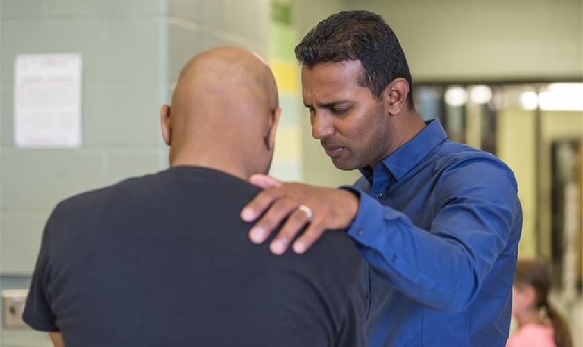 Kesavan Balasingham orando por um homem em sua igreja em Toronto, no Canadá. (Foto: NAMB)