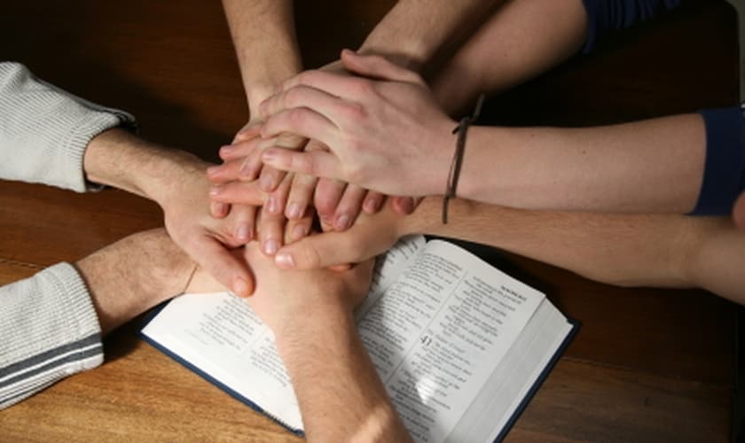 Mãos unidas sobre a Bíblia simbolizando a unidade da Igreja. (Foto: myocn.net)