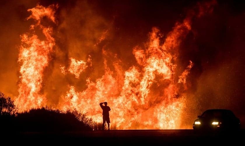 Motorista assiste as chamas do incêndio Thomas ao norte de Ventura, na Califórnia. (Foto: AP/Noah Berger)