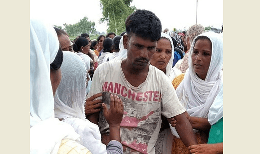 O pai de Anjali Masih sendo confortado por vizinhos. (Foto: WWM)