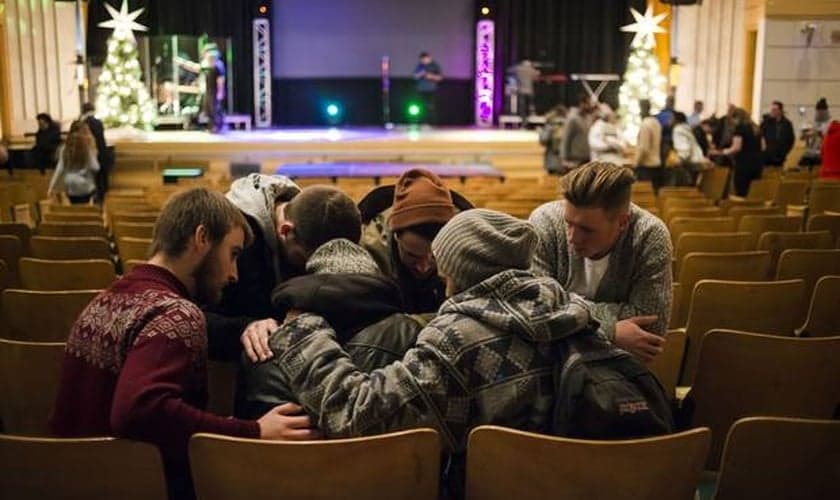 Jovens orando juntos após um culto evangélico em Toronto, no Canadá. (Foto: Christopher Katsarov/The Globe and Mail)
