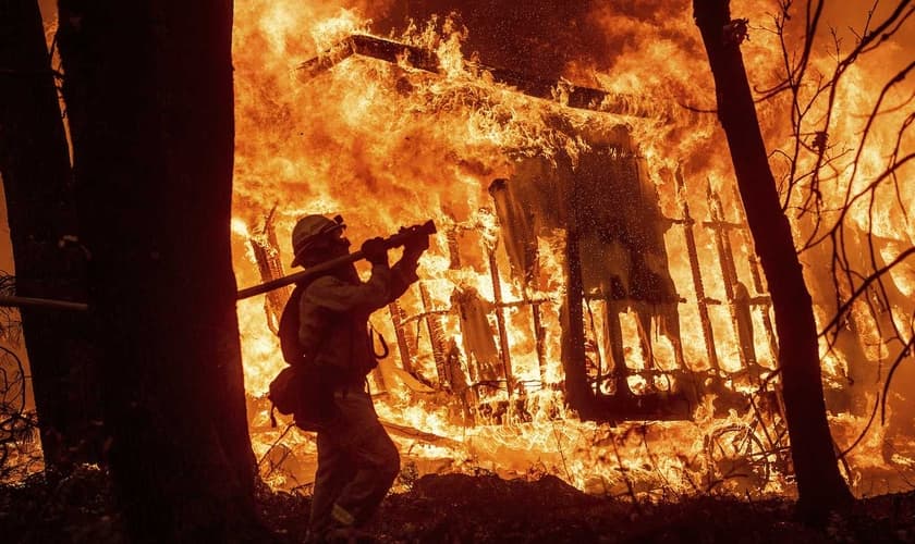 Bombeiro durante operação enquanto as chamas consomem uma casa em Magalia, na Califórnia. (Foto: Noah Berger/AP)
