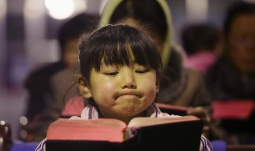 Criança lê Bíblia em igreja no vilarejo de Gaojiabao, na China. (Foto: Jason Lee/Reuters)