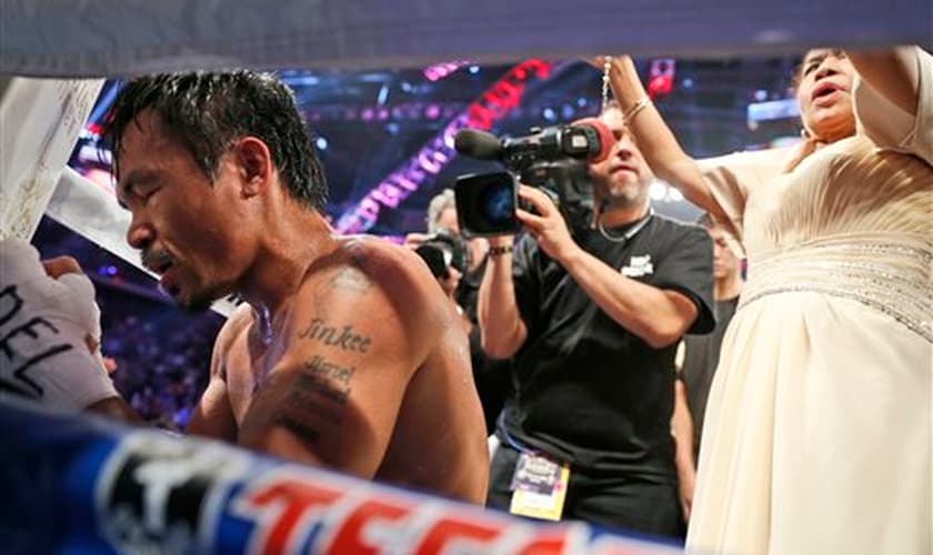 Manny Pacquiao em oração após disputa pelo título dos meio-médios em Macau, na China, em 2014. (Foto: AP)