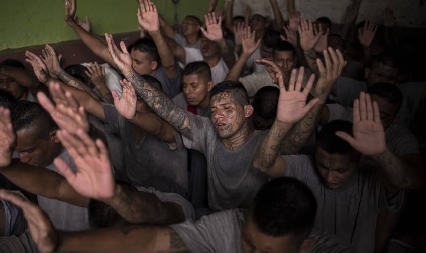 Antigos membros de gangues, presos na cadeia de Gotera, levantam as mãos durante o culto. (Foto: Victor Peña/El Faro)