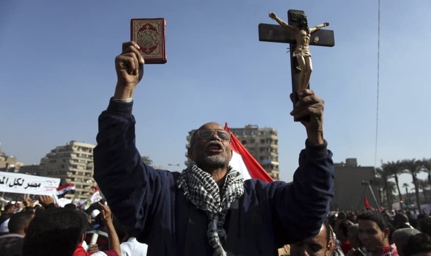 Manifestante egípcio segura uma cruz e um Alcorão em protesto na Praça Tahrir, no Cairo, Egito. (Foto: AP/Khalil Hamra)