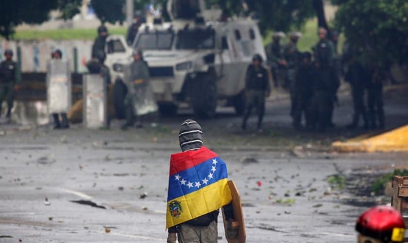 Manifestante de frente para as Forças Armadas em protesto contra Nicolás Maduro, na Venezuela. (Foto: Reuters/Carlos Garcia Rawlins)