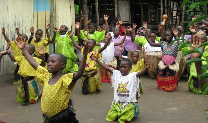 Crianças e adultos durante oração em comunidade de Uganda. (Foto: Set Free Ministries)