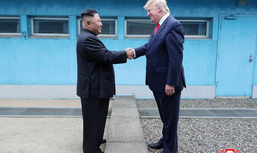 Trump em aperto de mãos com Kim na linha de demarcação que divide as duas Coreias. (Foto: KCNA via Reuters)