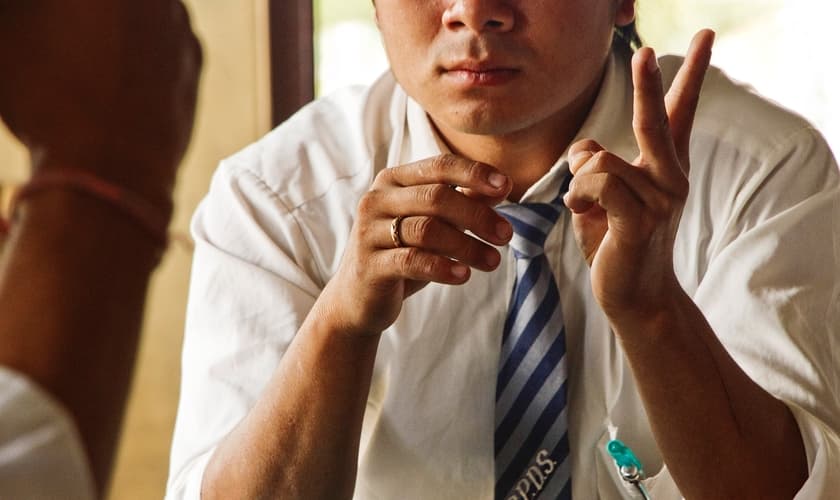 Aluno conversa em linguagem de sinais em uma escola para surdos na Tailândia. (Foto: Reprodução/IMB)