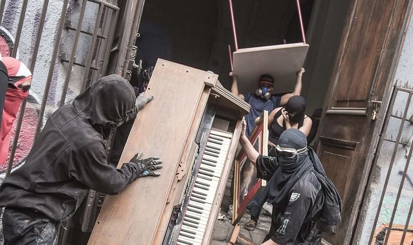 Imagens mostram manifestantes encapuzados saqueando uma igreja na região da La Assuncion. (Foto: Adrien Vautier / Le Pictorium Agency)