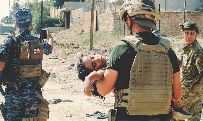 David Eubank carrega garota ferida em campo de guerra. (Foto: Fuller Studio)