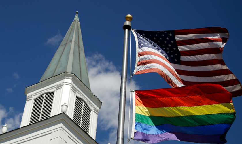 Bandeira do orgulho gay junto com a bandeira dos EUA em frente à Igreja Metodista Unida de Asbury, nos EUA. (Foto: AP)