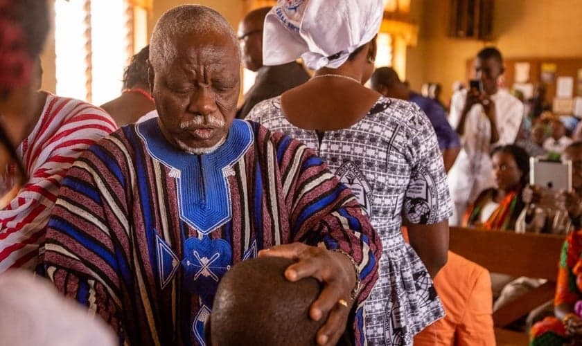O Taraana, um dos sete anciãos do chefe supremo, ora sobre seus colegas diáconos durante a ordenação deles na Primeira Igreja Batista, Nalerigu. (Foto: Reprodução/IMB)