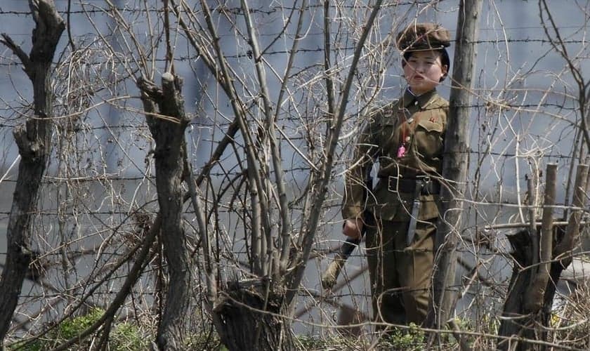 Policial norte-coreana guarda atrás de cercas em uma prisão às margens do rio Yalu. (Foto: Reprodução/Reuters)