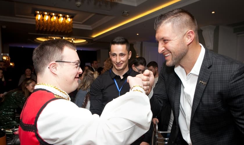 Tim Tebow cumprimenta um convidado na "Night to Shine", na Albânia. (Foto: Reprodução / Fundação Tim Tebow)