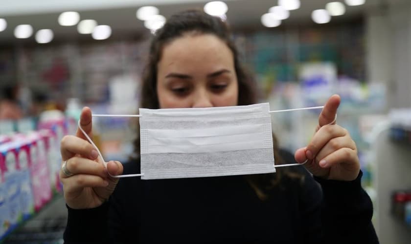 Vendedora mostra máscara de proteção, em Guarulhos (SP), usada diante da epidemia do novo coronavírus pelo mundo. (Foto: Amanda Perobelli/Reuters)