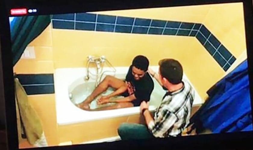 Akille sendo batizado na banheira de sua casa pelo pastor Reid Karr. (Foto: Reprodução/IMB)
