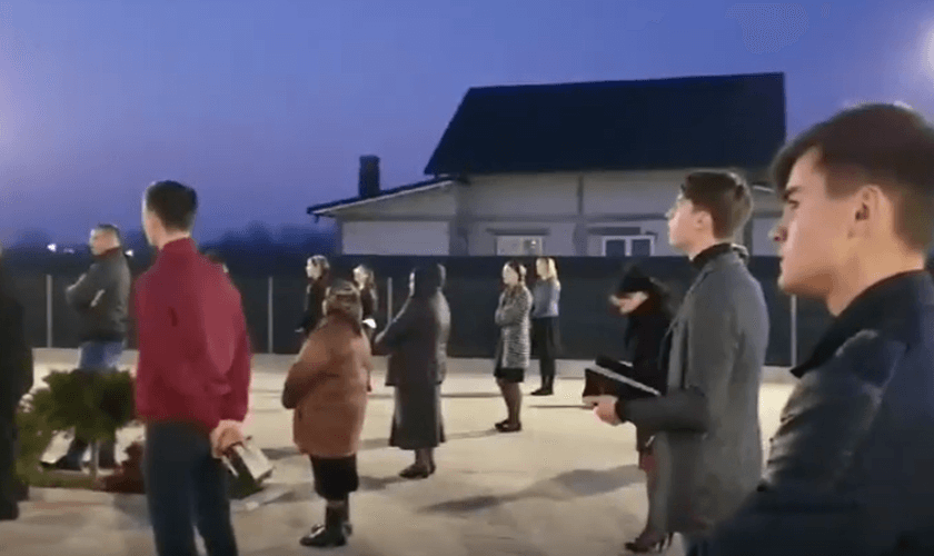 Membros da Igreja Cristã após o Evangelho de Sião, na vila de Prelipca, reunidos no estacionamento. (Foto: Reprodução/YouTube)