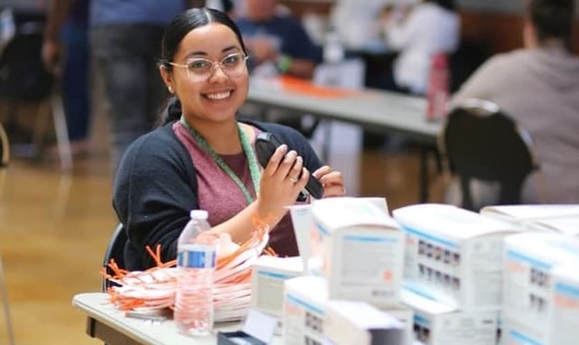 Voluntária da Rock Church troca elásticos de máscaras, respeitando o distanciamento necessário para evitar o contágio do coronavírus. (Foto: Rock Church / Facebook)