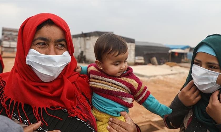 Mulheres usam máscaras em um campo para deslocados na província de Idlib. (Foto: Aaref Watad / AFP)