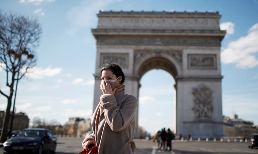 Mulher usa máscara de proteção perto do Arco do Triunfo, em Paris, na França. (Foto: Gonzalo Fuentes/Reuters)