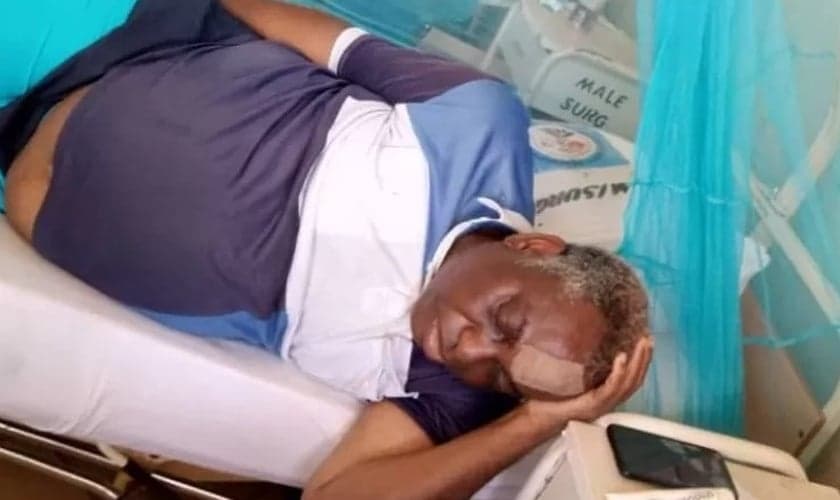 O Pr. Canon Famonure baleado com sua família ao orar dentro de sua casa. (Foto: Reprodução/Premier)