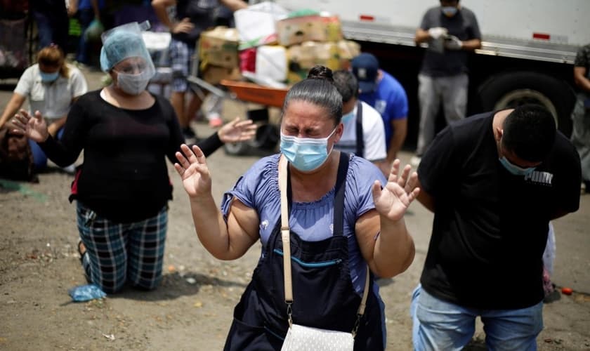 Fornecedores do maior centro de suprimentos de frutas e legumes de San Salvador em momento de oração. (Foto: EFE/Rodrigo Sura)