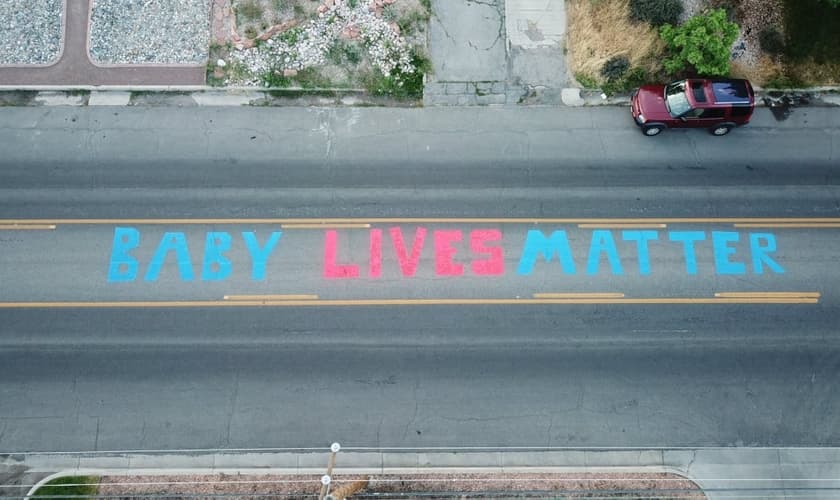 Antes que sua pintura fosse apagada, o artista Tayler Hansen conseguiu que seu protesto fosse registrado em frente à clínica de aborto da Planned Parenthood de Salt Lake City, Utah, EUA. (Foto: Twitter)