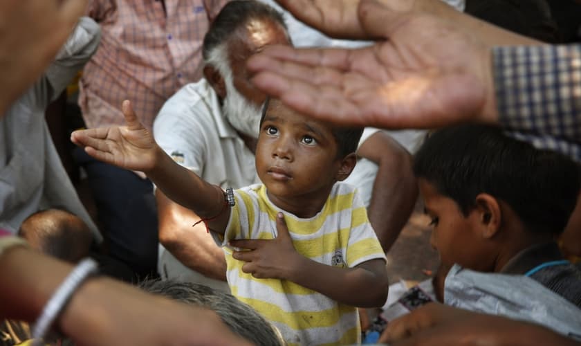 Criança estende a mão para receber comida em Nova Delhi, na Índia. (Foto: AP/Manish Swarup)