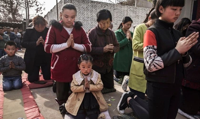 Cristãos chineses oram ajoelhados durante um culto de Páscoa em uma igreja não oficial. (Foto: Getty Images / Kevin Frayer)