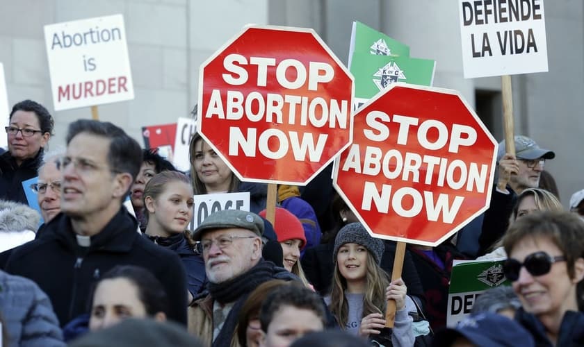 Manifestantes pró-vida protestam contra o aborto, segurando cartazes que dizem "Parem o Aborto Agora", enquanto ouvem os palestrantes em 23 de janeiro de 2017, no Capitólio em Olympia. (Foto: AP / Ted S. Warren)