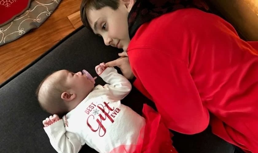 Owynn se deita ao lado da irmã mais nova, após vivenciar a emoção de ver suas orações atendidas. (Foto: Facebook)