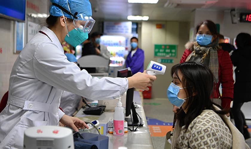 Profissional de saúde checa temperatura de mulher em um hospital de Fuzhou, na China. (Foto: Xinhua)