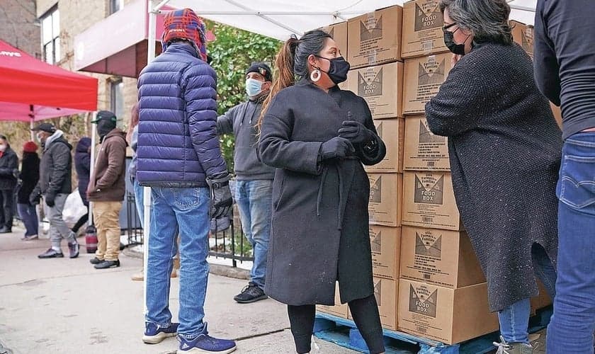A voluntária Gloria Martinez, à esquerda, fala com Sofia Moncayo, que dirige um programa de distribuição de alimentos por meio da Mosaic West Queens Church. (Foto: Emily Leshner / AP)
