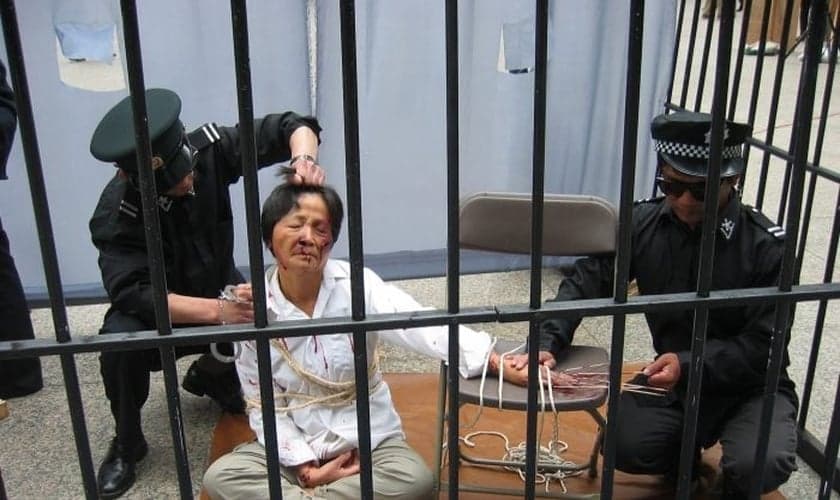 Reconstituição de um praticante do Falun Gong sendo torturado pela polícia em um centro de detenção. (Foto: Minghui.tv)