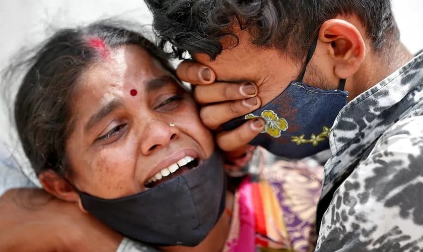 Mulher chora com seu filho depois que seu marido morreu devido à Covid-19 fora de um necrotério em Ahmedabad, na Índia. (Foto: Amit Dave / Reuters)