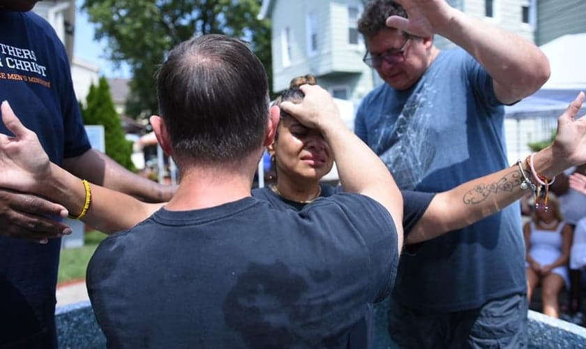 Pastor Steve Hannett ora por mulher durante batismo. (Foto: Abundant Grace Christian Church)