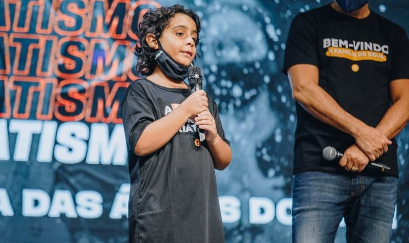 Arthur Ansuattigui, de 10 anos, conta testemunho ao lado do pastor Josué Valandro Jr. (Foto: Igreja Batista Atitude)